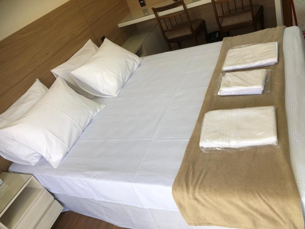 quarto do Flat de luxo em Lagoa Santa/MG, com cama de casal com travesseiros, toalhas e uma mesa com cadeiras ao lado