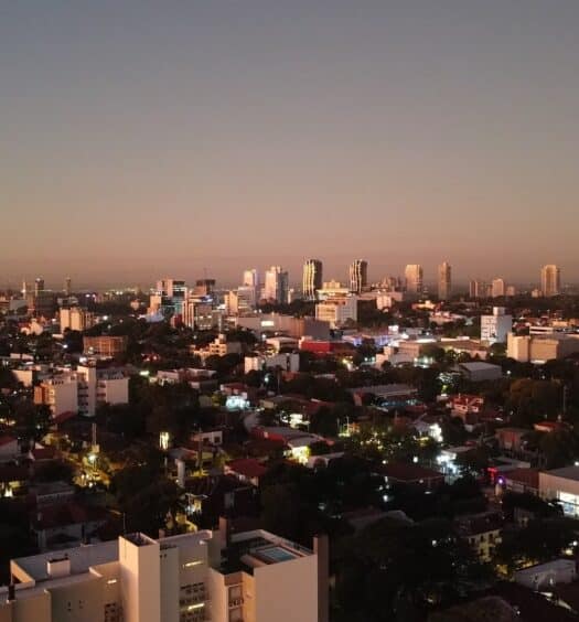 Vista aérea de Assunção, com construções (casas e prédios) em um dia anoitecer.