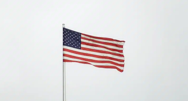 Bandeira dos EUA na Embaixada do país norte-americano na Alemanha, totalmente estendida devido ao vento em um dia nublado, para ilustrar a capa do post sobre entrevista do visto americano