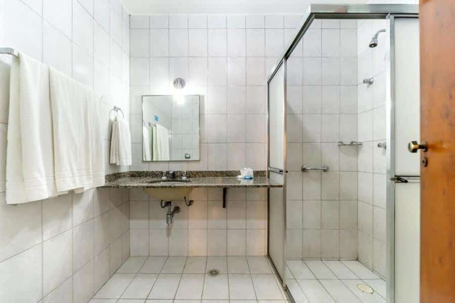 Banheiro do Itapetinga Hotel com barras de segurança no chuveiro e pia baixa.