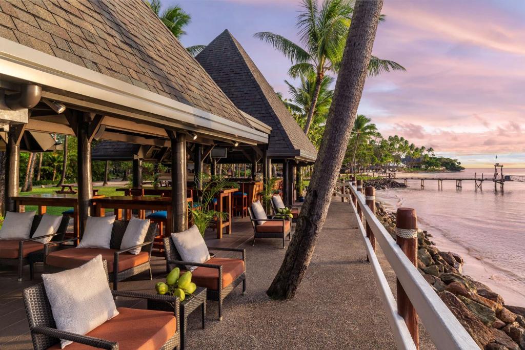 Vista da área de lazer do Shangri-La Yanuca Island durante o dia com cadeiras e coqueiros com vista para a praia. Representa hotéis em Fiji.