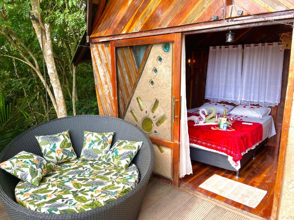 Vista de frente do TerrAmor Amazon com sofá em frente ao chalé com portas abertas e dentro do chalé uma cama de casal.