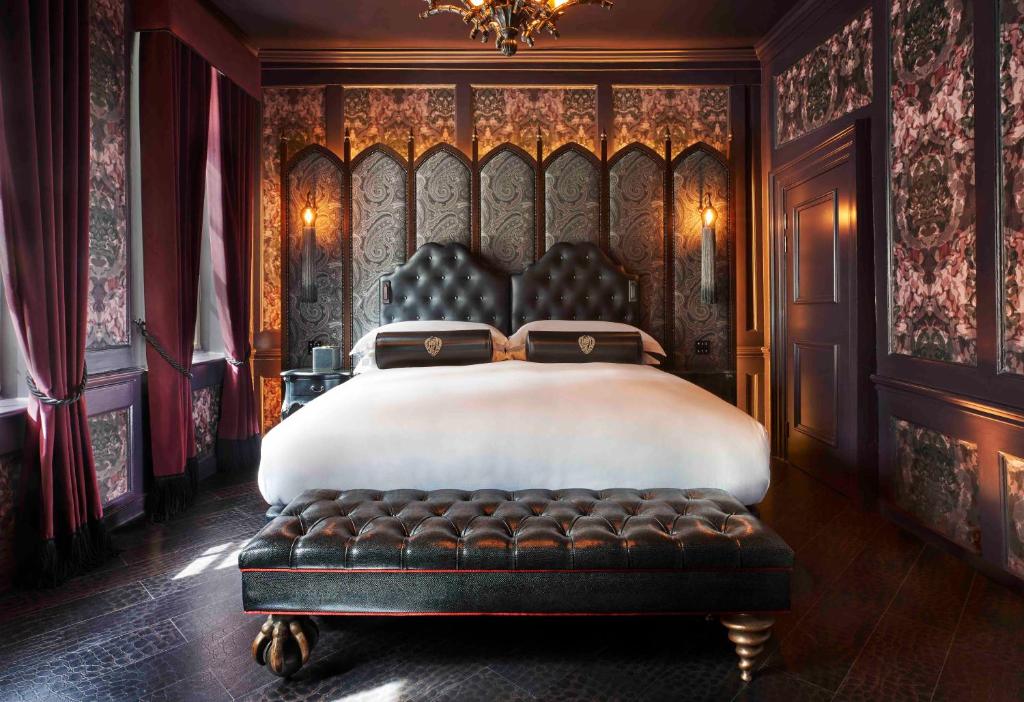 Quarto do Chateau Denmark  inteiro em estilo europeu, com papéis de parede decorativos, cabeceira de couro na cama de casal, um móvel de couro para se sentar, cortinas vermelhas nas janelas e um lustre sob a cama