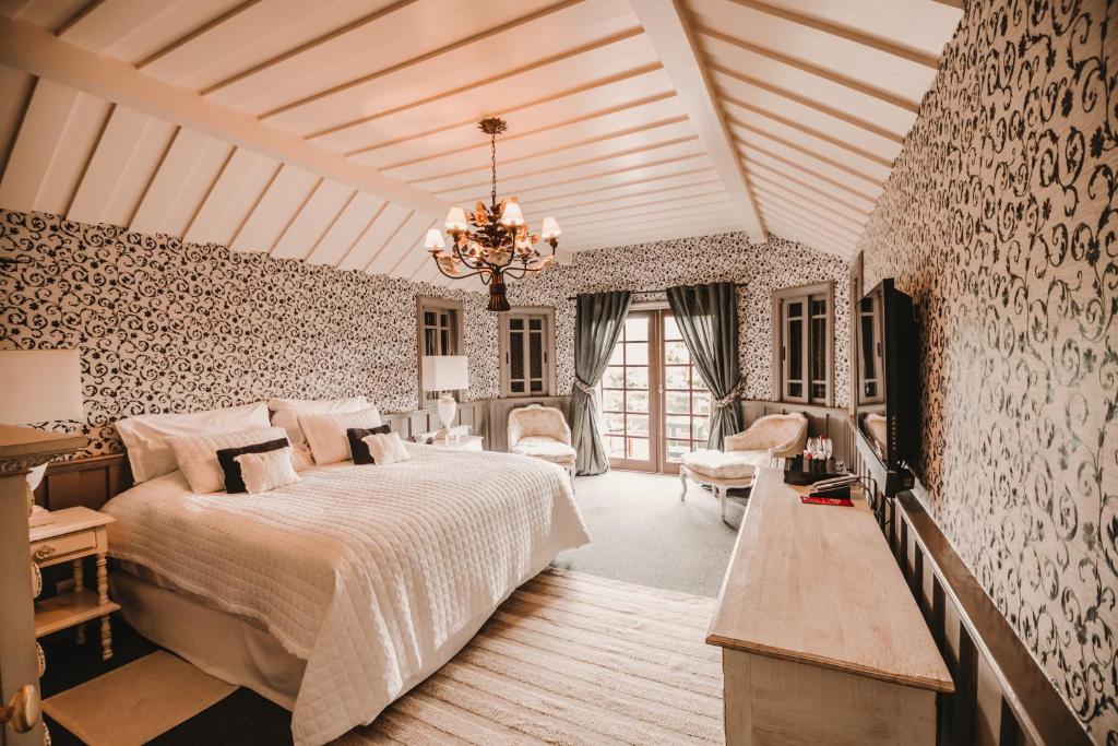 Quarto amplo do Chateau La Villette com uma sacada, duas poltronas, um lustre, uma cama de casal, um móvel de madeira com uma televisão, para representar onde ficar em Campos do Jordão