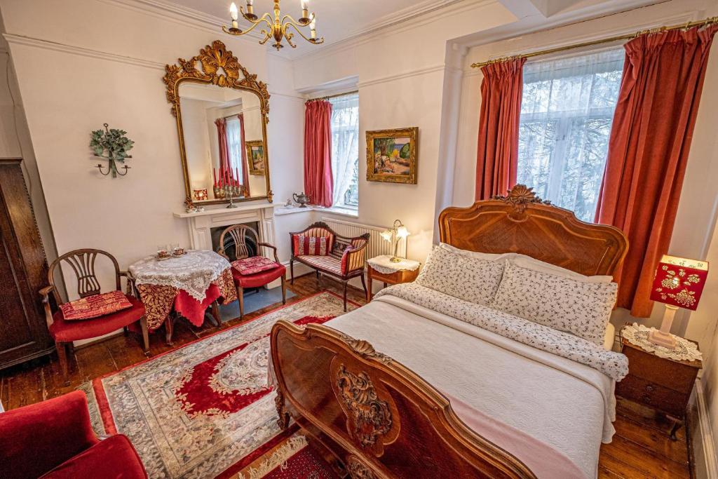 Quarto do Dawson Place, Juliette's Bed and Breakfast com decoração renascentista, tudo em vermelho e bege, a cama é de madeira, há duas janelas com cortinas vermelhas, um tapete branco com vermelho, e duas poltronas, há também um espelho e um lustre, em Londres