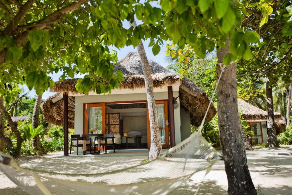 Frente do Castaway Island com mesa em frente com cadeiras, rede e chão de areia durante o dia. Representa hotéis em Fiji.