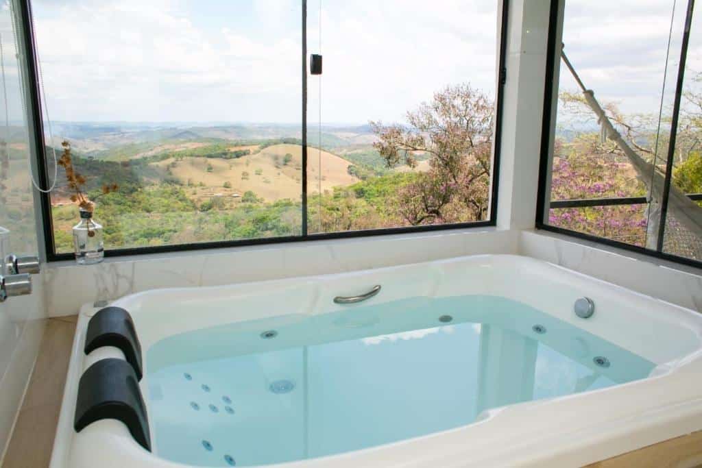banheira de hidromassagem do Loft Paraíso da Serra com duas janelas amplas que dão vista para o vale mineiro