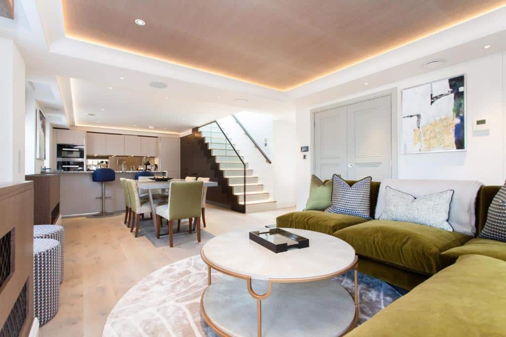 Sala de estar junto com cozinha compacta no Hope House Residences by Q Apartments com uma escadaria do lado direito, e há sofás com almofadas e uma mesa de centro, em Londres