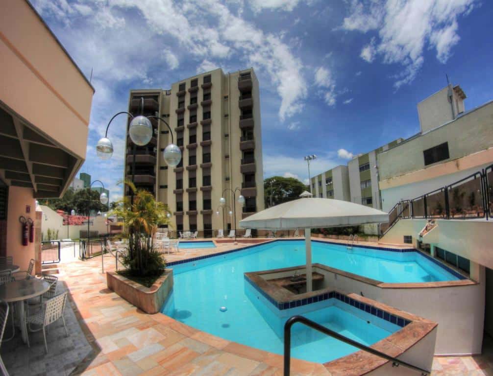 Vista das piscinas do Hotel Ema Palace, uma das opções de hotéis em São José dos Campos, com prédio ao fundo e um dia de céu azul com nuvens