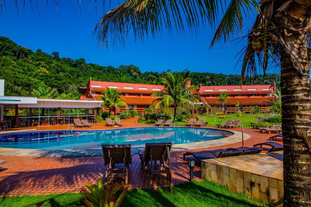 Vista da piscina do Hotel Boutique Frangipani durante o dia com a piscina ao centro com cadeiras de madeira em volta e ao fundo o hotel.