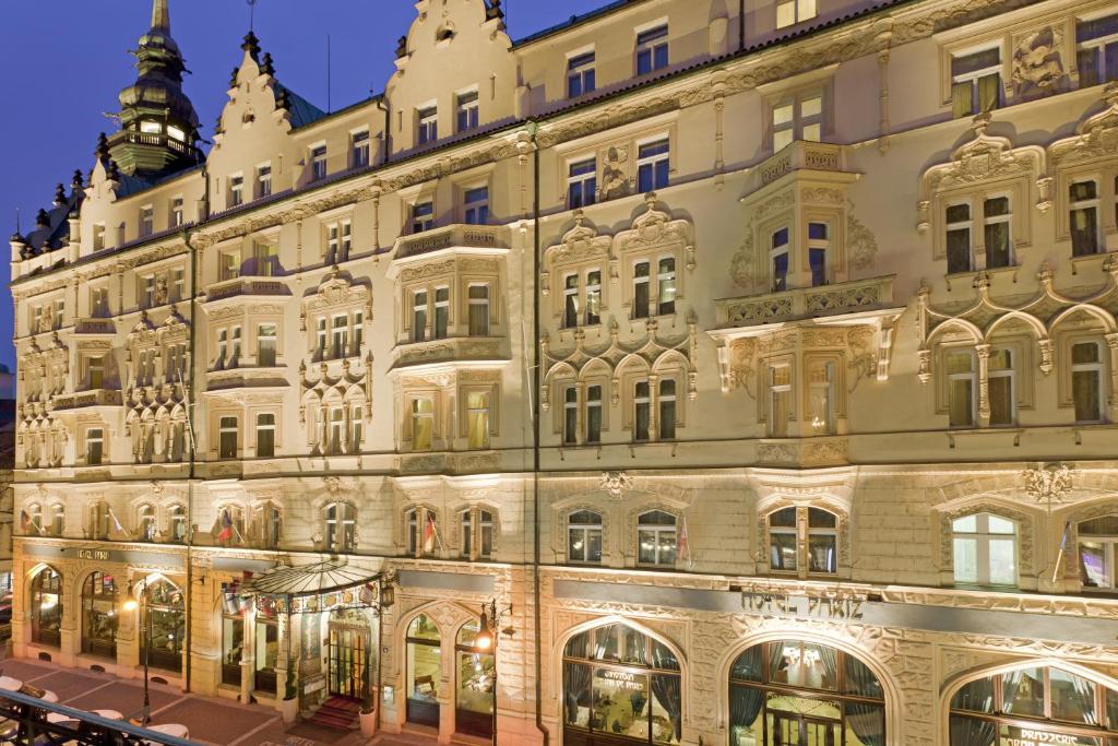 Prédio do Hotel Paris Prague em estilo renascentistas, com seis andares, janelas amplas e alguns desenhas próximos dela, para representar hotéis em Praga