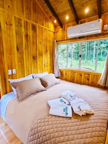 quarto das Cabanas Imbuia com uma janela ampla com vista para a natureza e um ar-condicionado em cima da janela