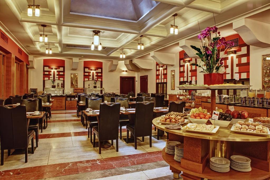 Área de refeições do Majestic Plaza Hotel Prague com cadeiras e mesas de madeira, com alguns lustres e locais para se servir
