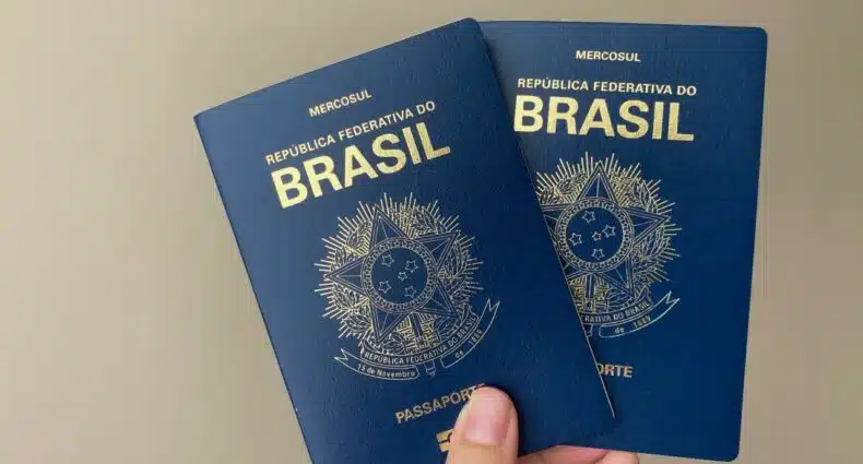 Capa azul marinho nos passaportes brasileiros, sendo uma mão segurando duas unidades do documento, para ilustrar a capa do post "como tirar passaporte"