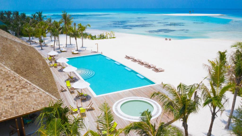 piscina com espreguiçadeiras ao redor e piscina menor circular circundado de palmeiras e saída direto para o mar de águas cristalinas do Innahura Maldives Resort, um dos resorts nas Maldivas