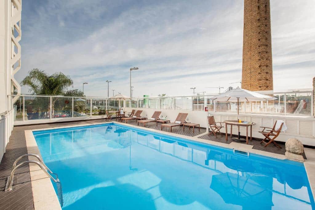 piscina retangular no terraço do Intercity Florianopolis, um dos hotéis perto do aeroporto de Florianópolis, com mesinhas e cadeiras