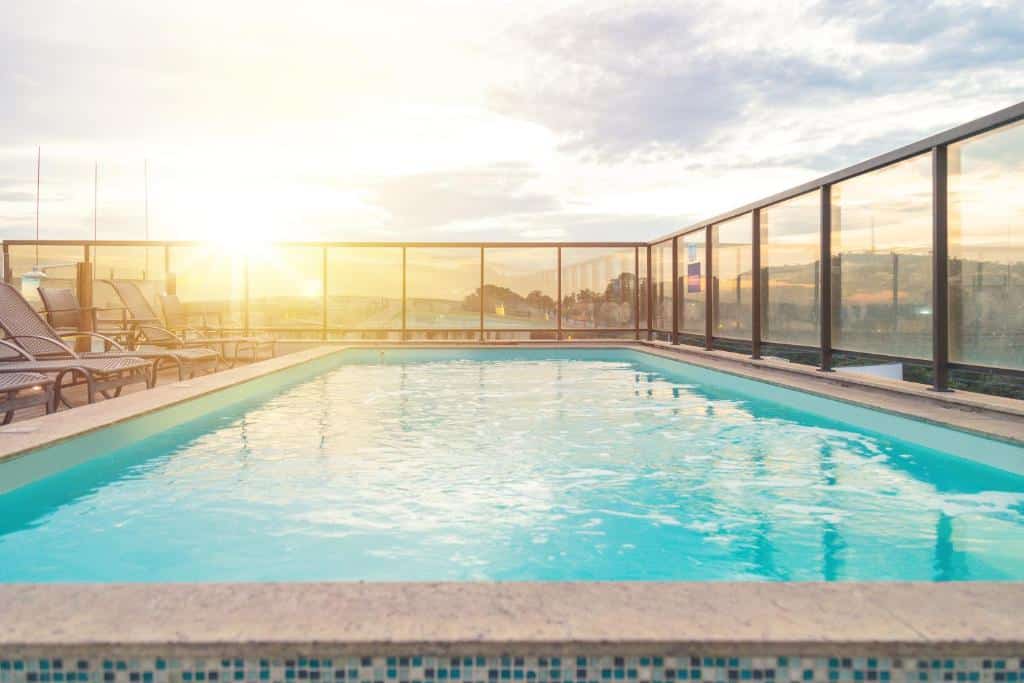 piscina do Lagoon Prime Hotel, um dos hotéis perto do Aeroporto de Confins, ao pôr do sol, no terraço, com vidros nas bordas e cadeiras
