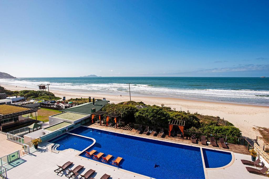 vista do Slaviero Ingleses Convention, um dos hotéis perto do Aeroporto de Florianópolis, com piscina retangular grande com espreguiçadeiras e vista para o mar