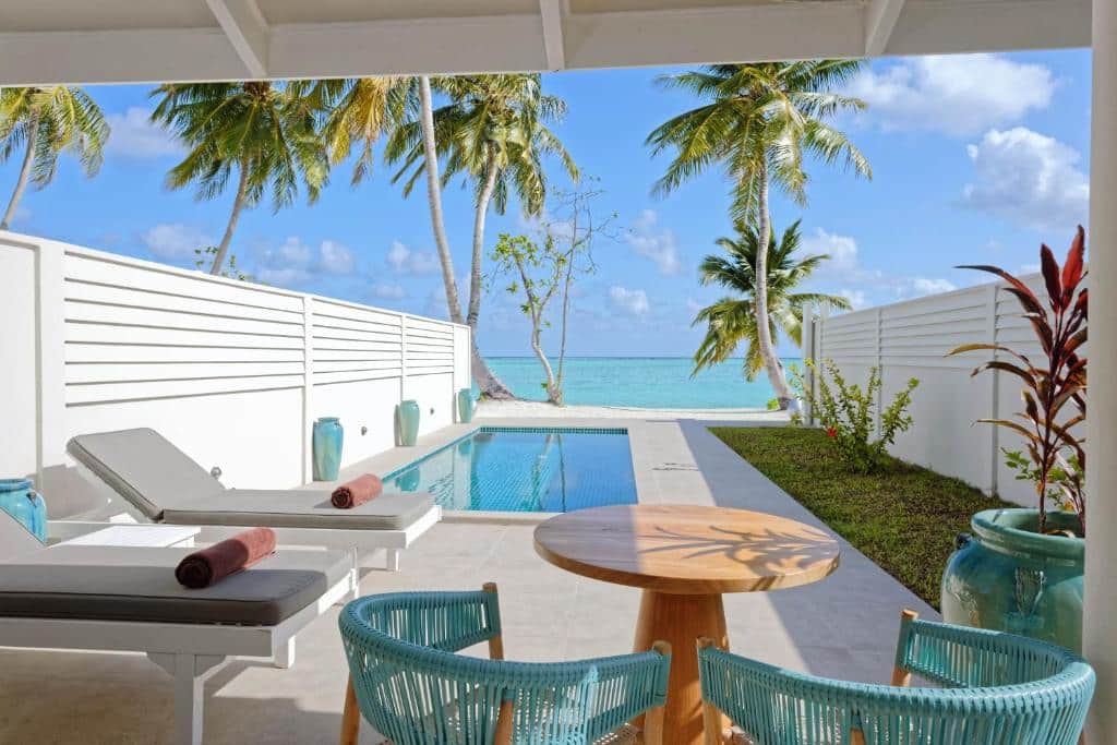 piscina privativa na varando do quarto do Sun Island Resort & Spa, um dos resorts nas Maldivas, com mesa e cadeiras e espreguiçadeiras, tudo com vista para o mar e palmeiras