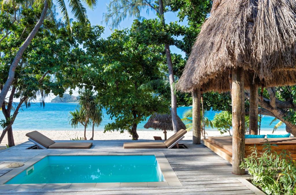 Vista da piscina do Paradise Cove Resort à beira-mar durante o dia com poltronas perto da piscina. Representa hotéis em Fiji.
