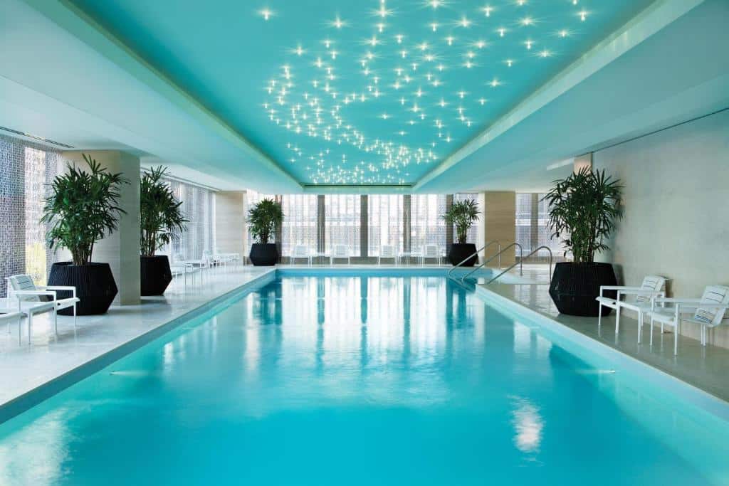 Vista da piscina coberta do The Langham com vasos de plantas em volta com cadeiras brancas. Representa hotéis em Chicago.