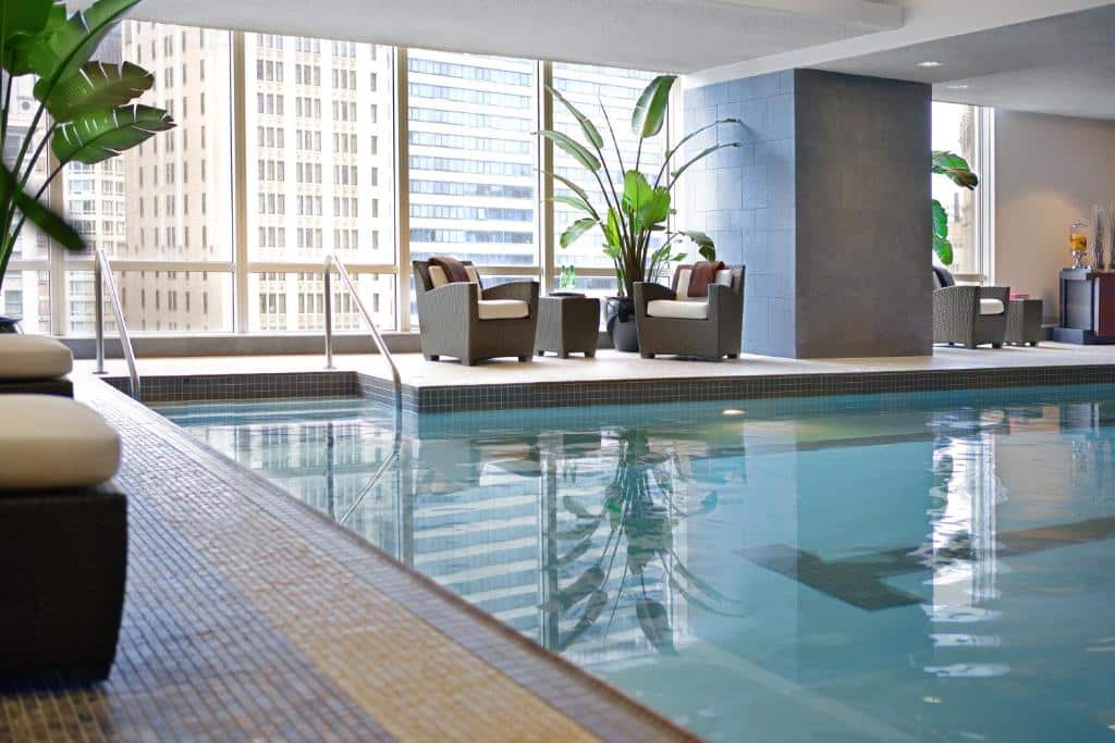 Vista da piscina coberta do Trump International Hotel & Tower com poltronas do lado esquerdo perto das janelas de vidro que tem vista para a cidade. Representa hotéis em Chicago.