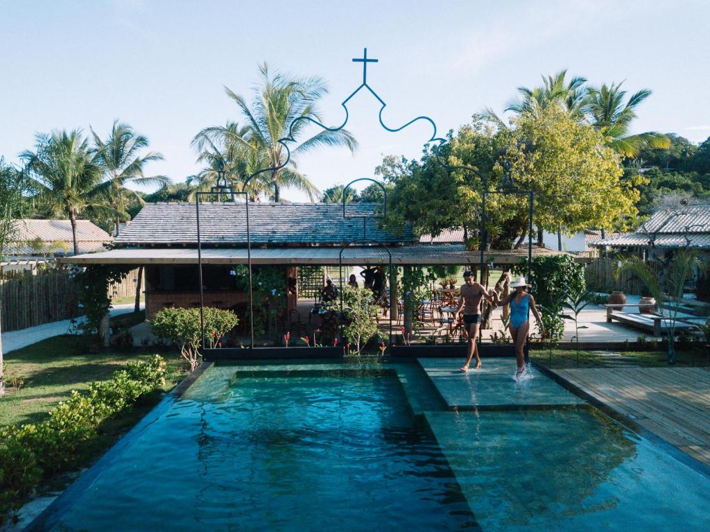 Piscina do Villa dos Nativos Boutique Hotel durante o dia com um casal na beira da piscina. Representa resorts em Trancoso.