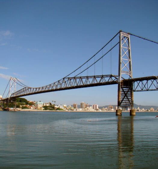 vista da Ponte Hercílio Luz, perto do Aeroporto de Florianópolis, com águas tranquilas abaixo, em uma estrutura de metal bem elaborada da ponta