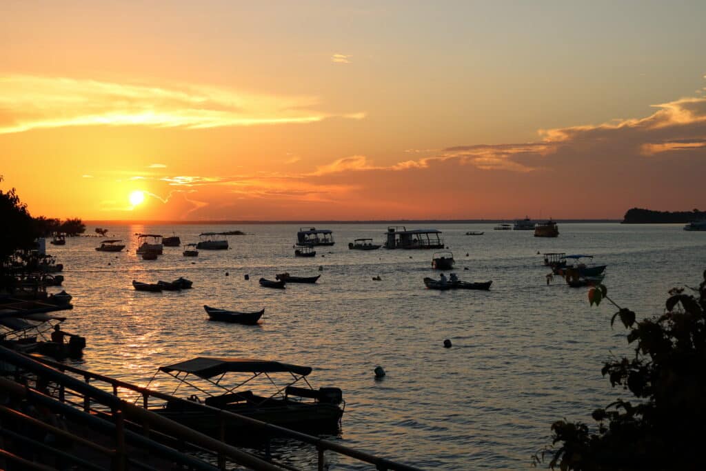 Vista do Pôr do sol, em Alter do Chão, Pará, com vários barcos dentro do rio.