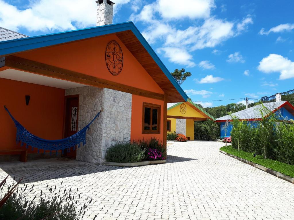 Casa laranja com rede azul e outras casas coloridas em volta durante o dia, ilustrando post pousadas em Visconde de Mauá.