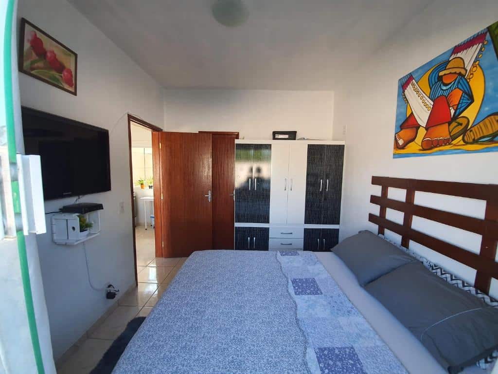 quarto do Apartamento próximo ao Aeroporto de Florianópolis com cama de casal, tv em frente, e guarda-roupa com espelho