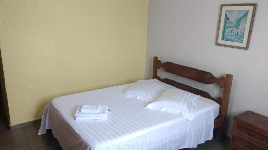 quarto do Hotel Lund um dos hotéis perto do Aeroporto de Confins, com cama de casal e mesinha de cabeceira