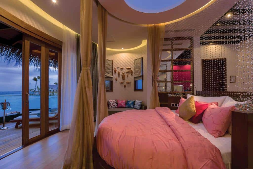quarto do OBLU SELECT Sangeli com cama redonda em detalhes em rosa, muitas almofadas e bem decorado e varanda com vista para o mar