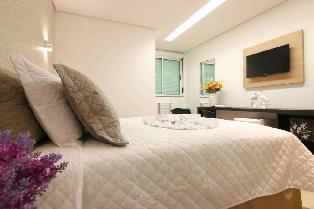 quarto do Tupyguá Brasil Hotel com cama de casal, mesa de trabalho, tv e janela de vidro