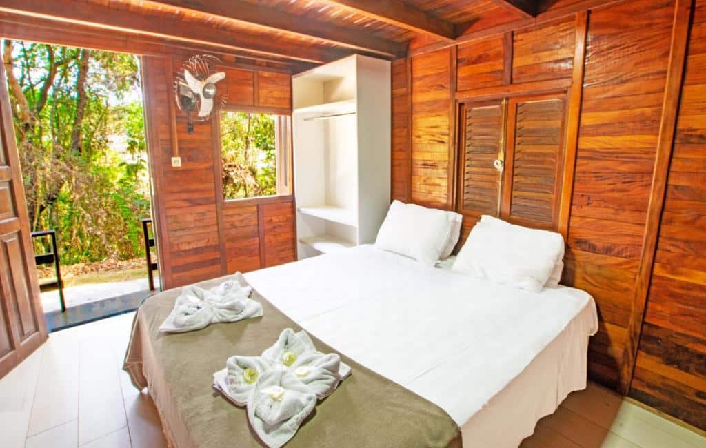 Quarto da Cabana’s Acqua Hotel com cama de casal do lado direito, e ao lado uma cômoda de madeira branca.