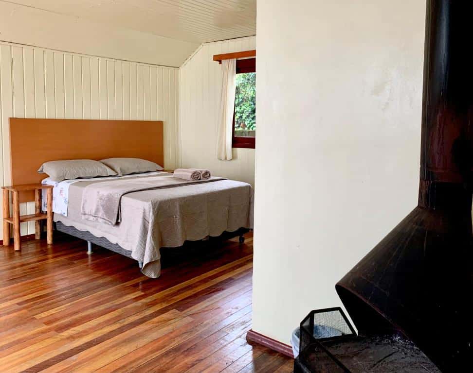 quarto do Central Chalés com uma lareira à direita e uma cama de casal simples à esquerda