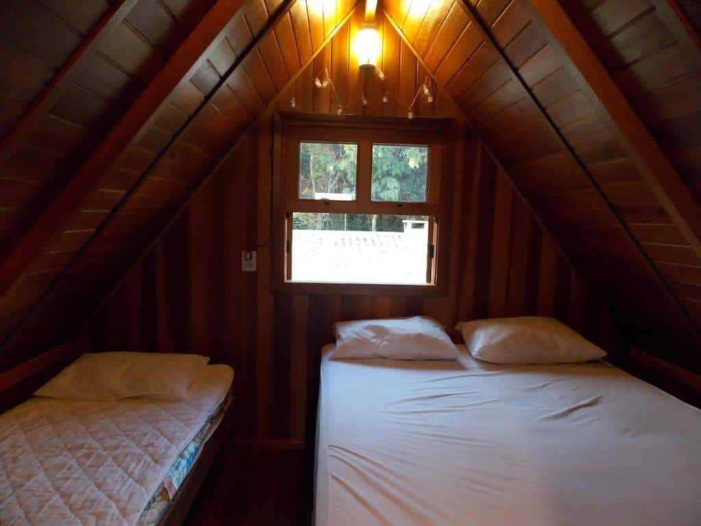 Quarto do Chalé Paraíso com acomodações simples com uma cama de casal do lado direito e do lado esquerdo uma cama de solteiro.