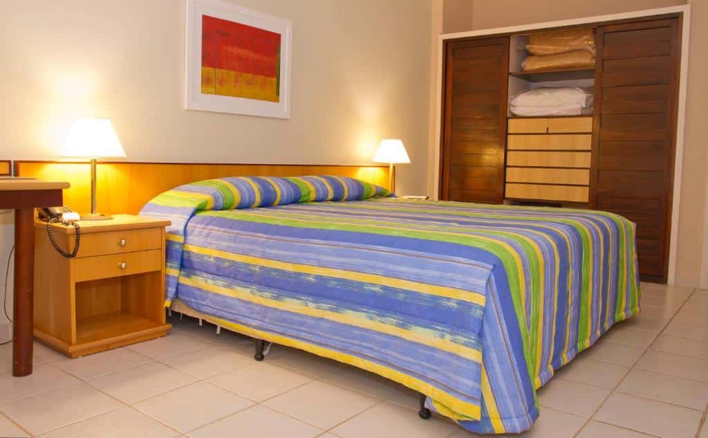Quarto do Eldorado Atibaia Eco Resort  com cama de casal, duas cômodas ao lado com luminárias e um guarda roupa do lado esquerdo.