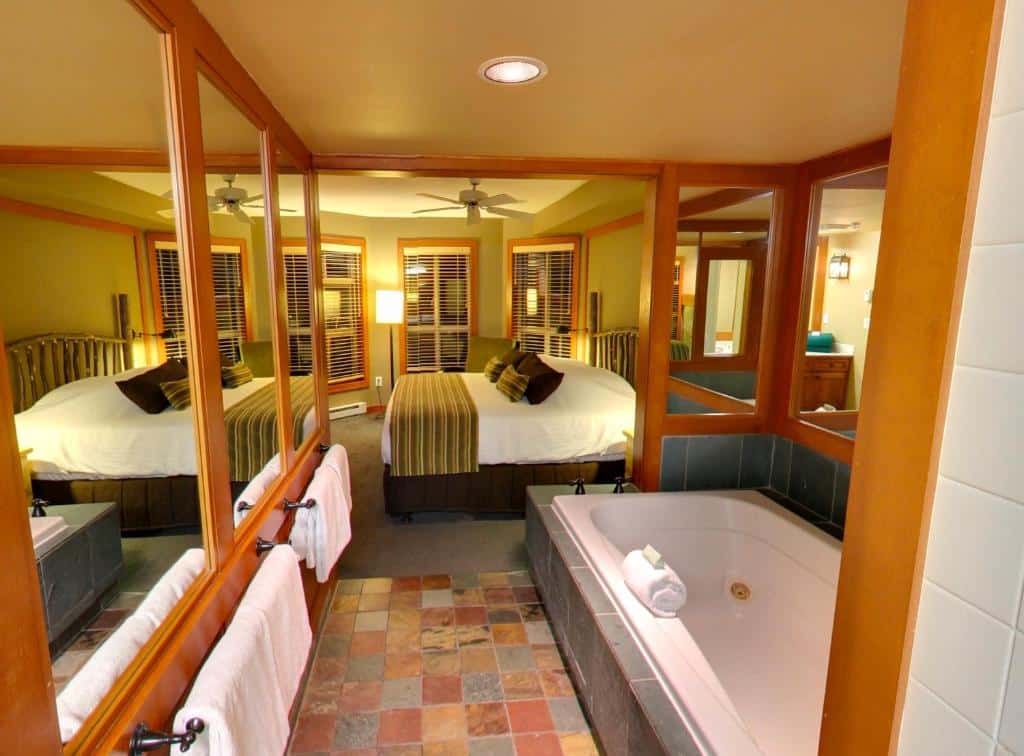 Quarto do Hilton Grand Vacations Club Whistler com uma banheira, uma cama de casal, algumas janelas com persianas e um ventilador de teto