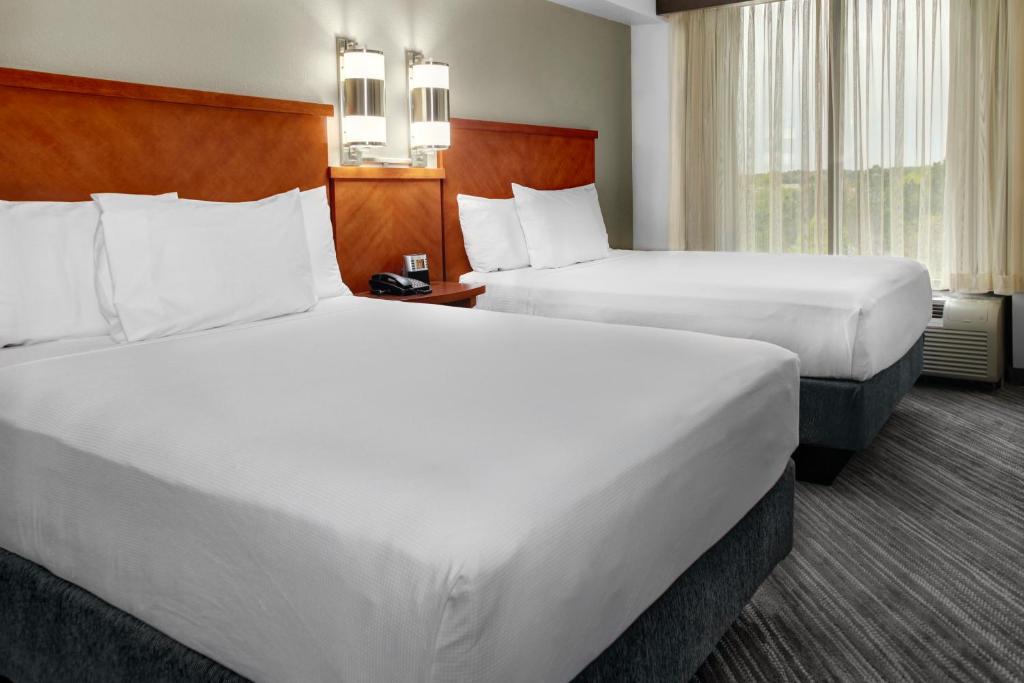 Quarto do Hyatt Place Tampa Busch Gardens com uma cama de casal e uma de solteiro, uma janela com cortinas e um ar-condicionado de parede