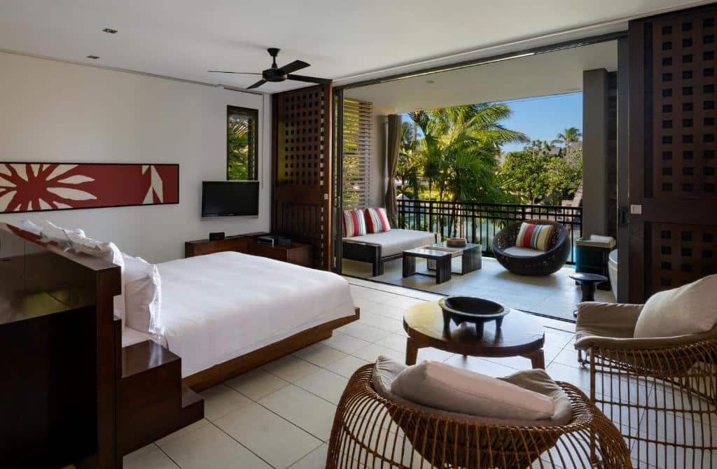 Quarto do InterContinental Fiji Golf Resort & Spa com cama de casal e em frente a cama varanda com área de estar com poltronas.