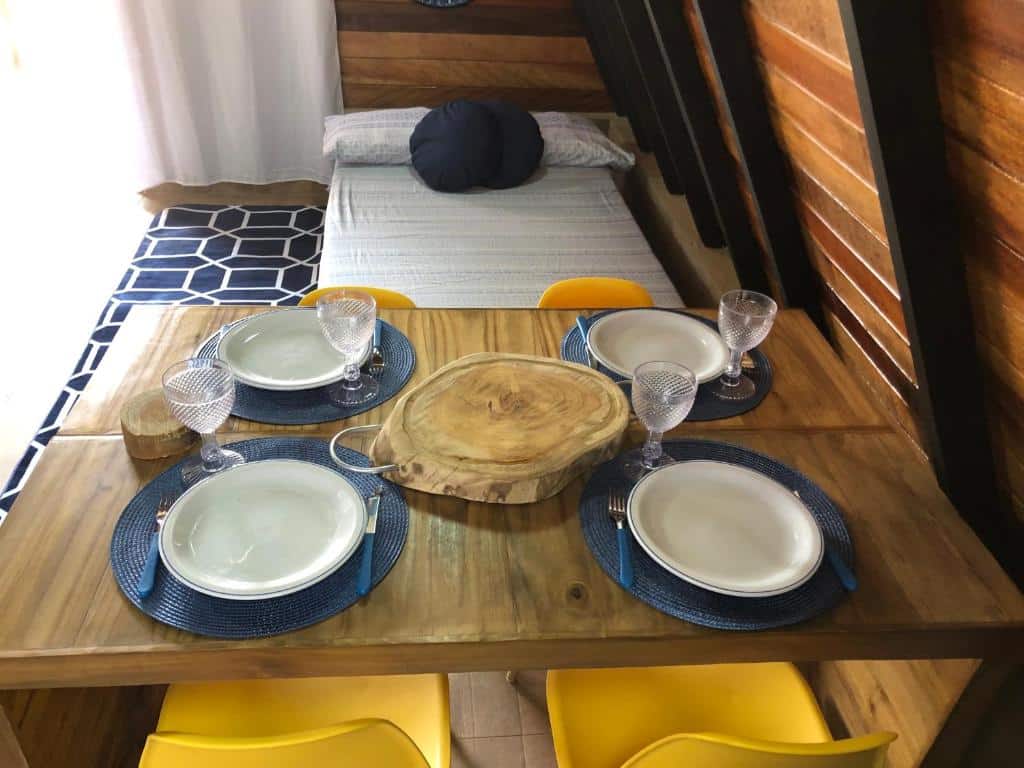 Quarto do Chalé Na coruja jacuzzi SPA com mesa de madeira com louça em cima da mesa com copos, e ao fundo um colchão de casal no chão.