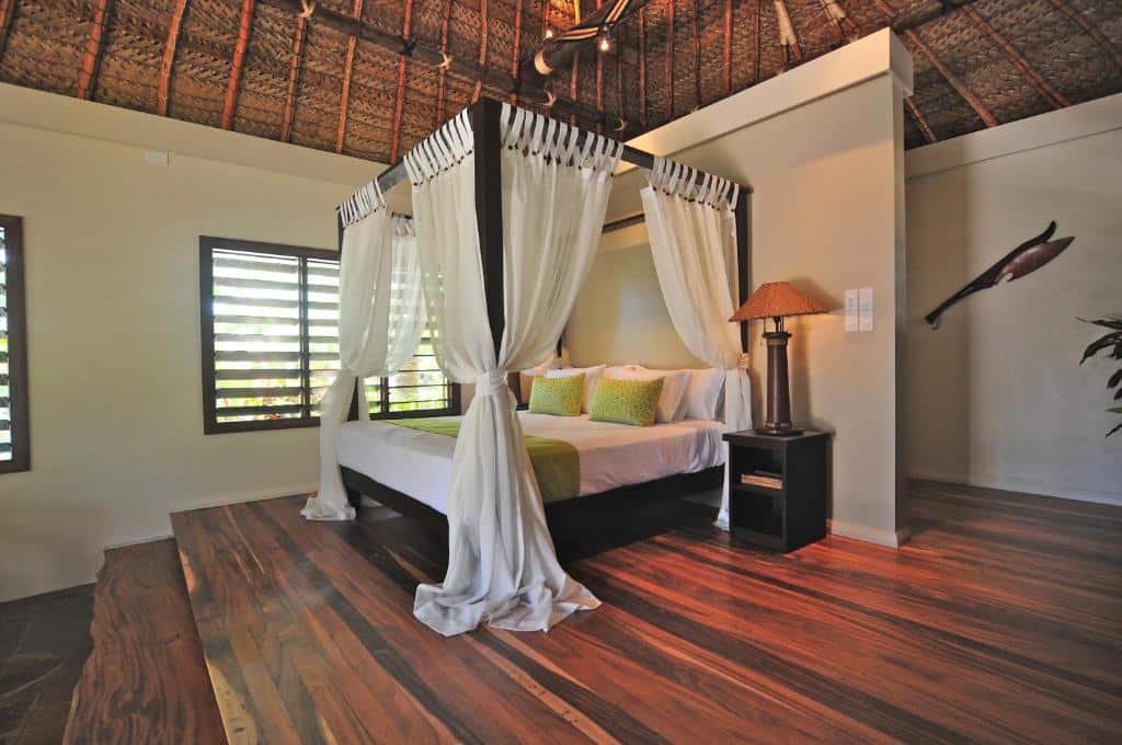 Quarto do Paradise Cove Resort com cama de casal e uma cômoda do lado direito com luminária.