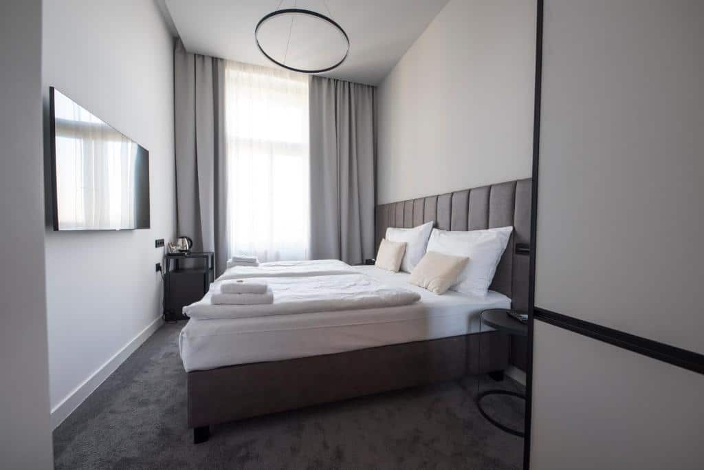 Quarto do The Gold Bank  com uma cama de casal, uma janela com cortinas, uma televisão e um carpete cinza, para representar hotéis em Praga