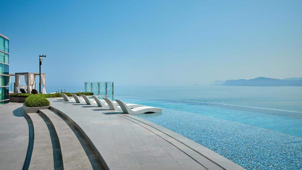 Piscina com borda infinita do Signiel Busan com vista para o mar e algumas espreguiçadeiras numa área mais alta da piscina, para representar hotéis na Coreia do Sul