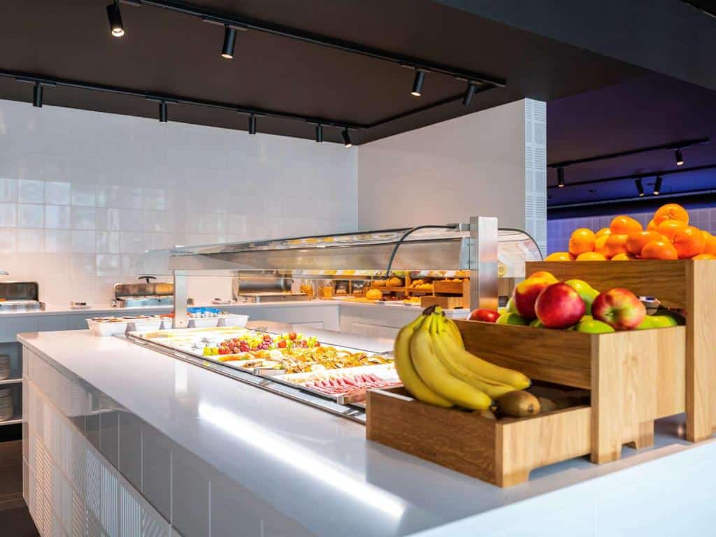 Balcão branco e iluminado com frutas e café da manhã do hotel Mercure Amsterdam