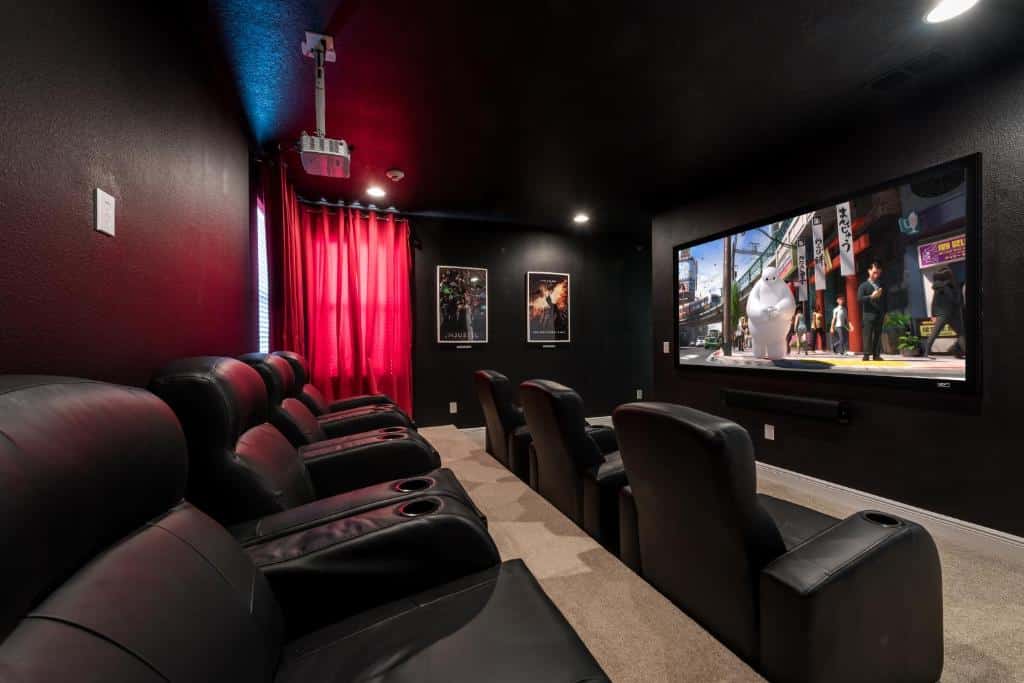 mini sala de cinema no Fabulous Home Near Disney with Private Pool, Movie Room, Themed Rooms & Resort Amenities, um das opções de aluguel de temporada em Orlando, com poltronas confortáveis de couro preto com porta copos e um projetor que reflete na TV