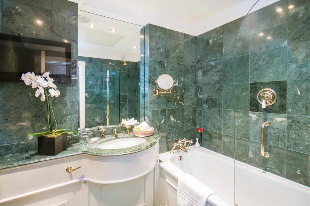 Banheiro do Egerton House com uma banheira de hidromassagem, uma pia e um espelho, para representar os melhores hotéis em Londres