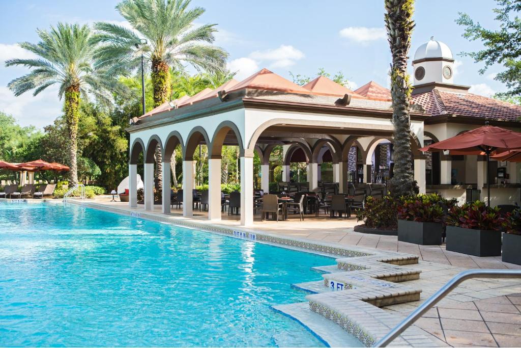 piscina retangular com uma tenda grande em que há mesas e cadeiras, há palmeiras ao fundo no Renaissance Orlando at SeaWorld, uma das opções de onde ficar em Orlando