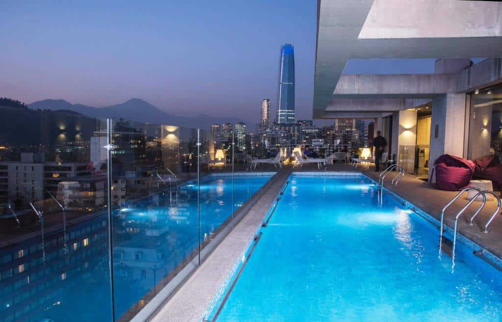 Piscina do Solace Hotel durante a noite com vista para a cidade. Representa hotéis em Santiago.